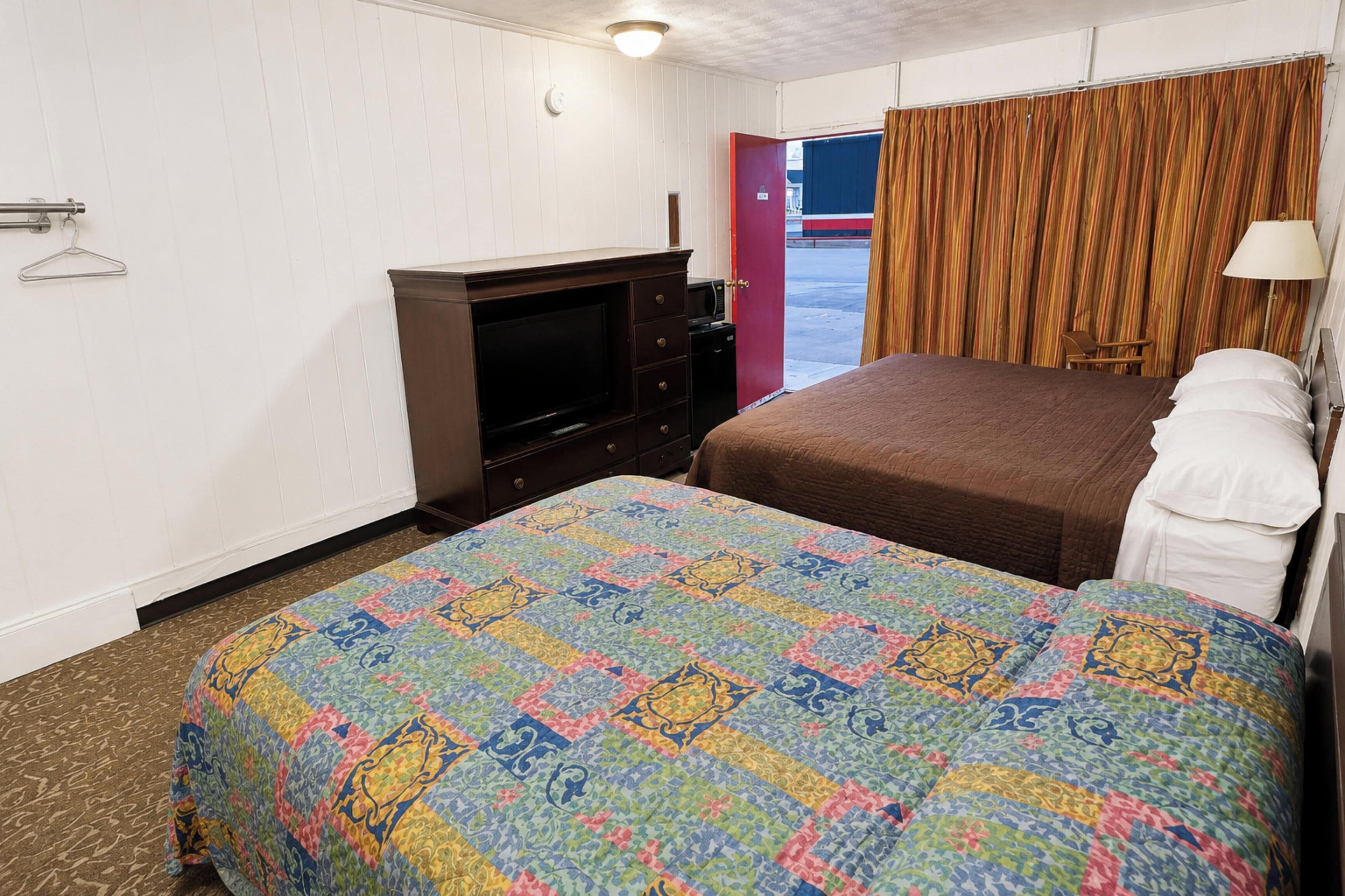 Una habitación de hotel con cama, televisión, cómoda y vistas al exterior.