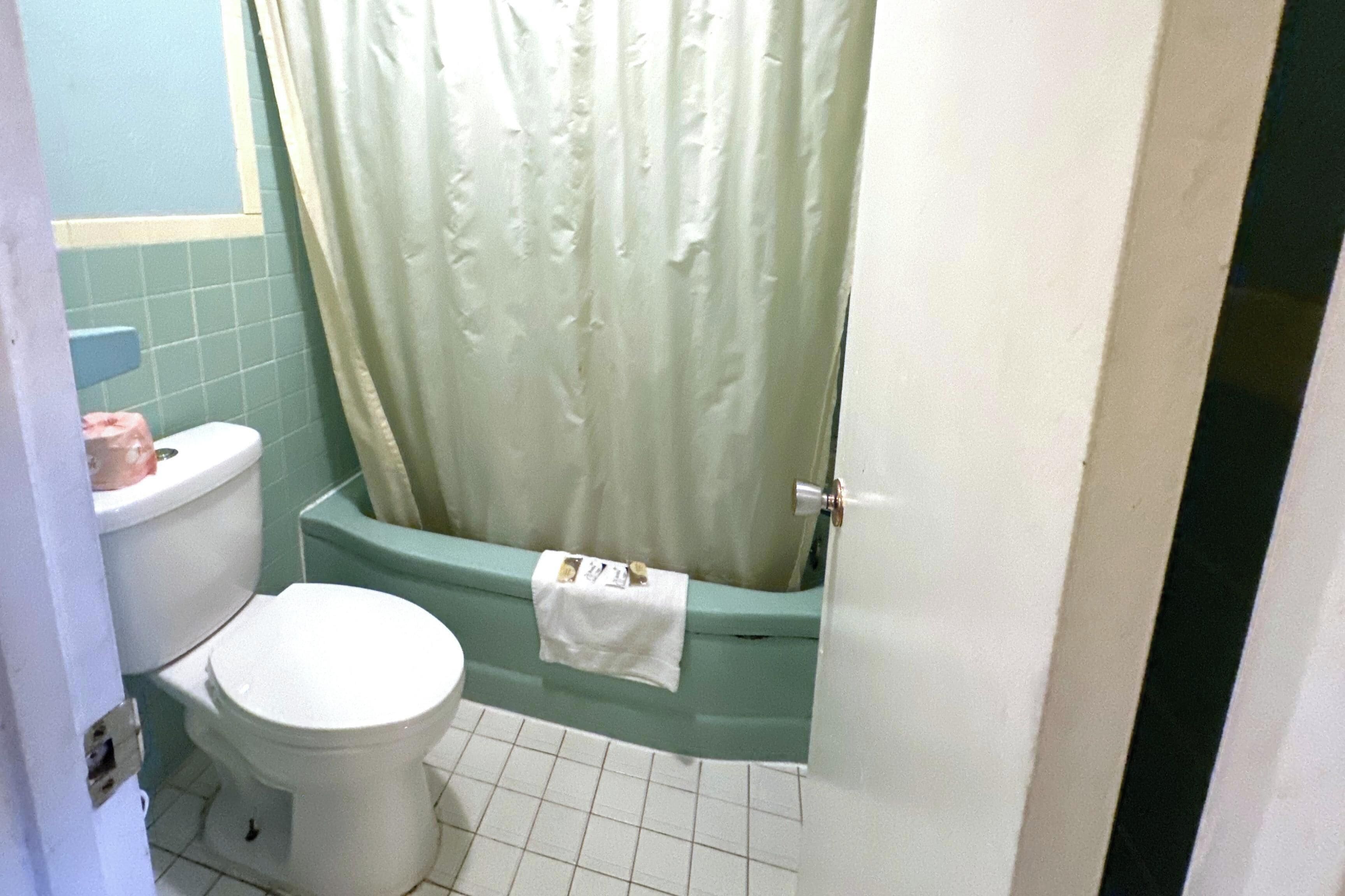 Un baño con inodoro, bañera y cortina de ducha.