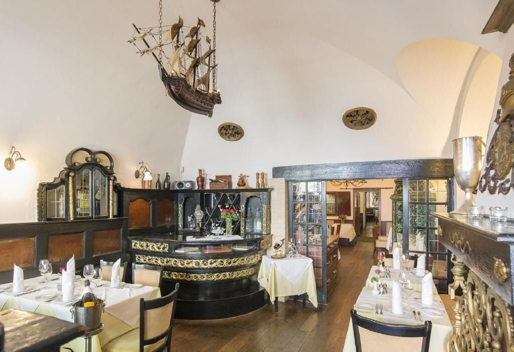 A restaurant interior with a central bar, wooden paneling, and a ship hanging from the ceiling.