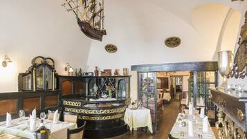 A restaurant interior with a central bar, wooden paneling, and a ship hanging from the ceiling.