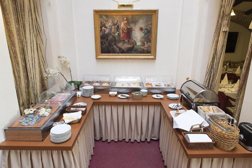 A buffet setup with various food items, a painting on the wall, and a mirror reflecting the room.