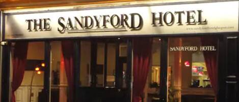 Het uiterlijk van Hotel Sandford, met de naam duidelijk zichtbaar boven de ingang.