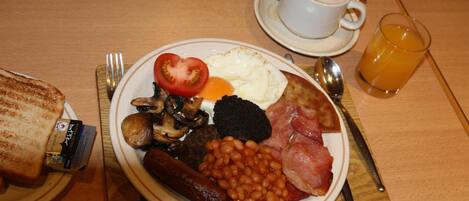 A breakfast plate with toast, eggs, beans, sausages, and ham.