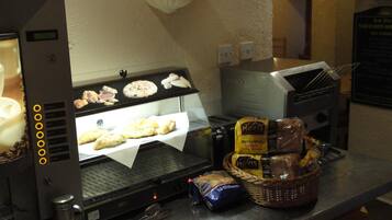 A kitchen area with a sandwich maker, a toaster, and a basket of bread and condiments.