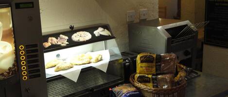A kitchen area with a sandwich maker, a toaster, and a basket of bread and condiments.