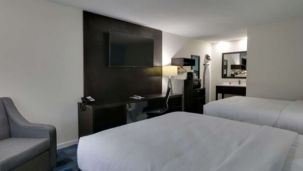 Hotelkamer met twee bedden, een bureau, een flatscreen-tv, een stoel, een lamp en een spiegel.