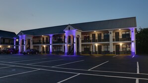 Een hotel met meerdere verdiepingen en een parkeerplaats.