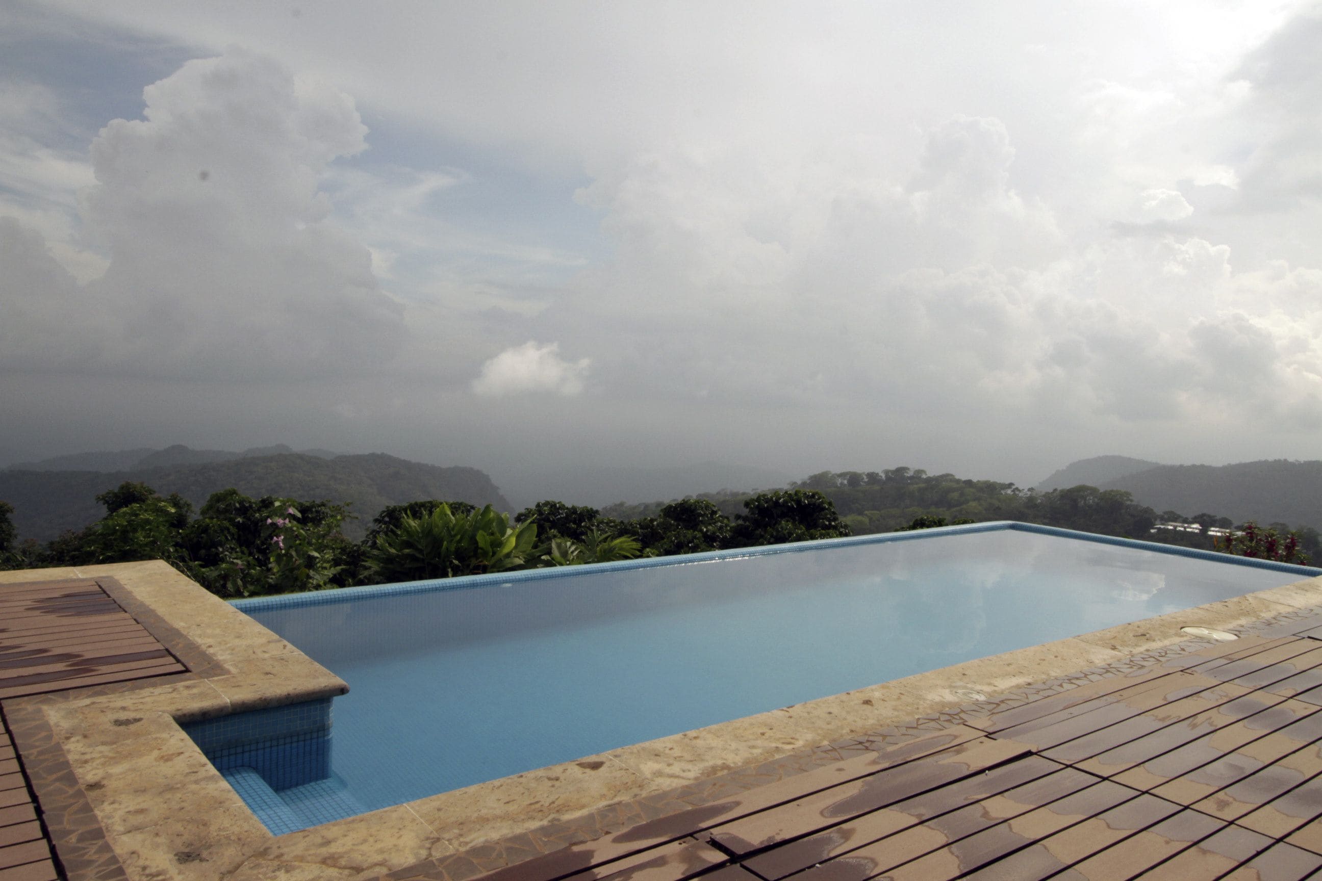A rectangular pool with a tiled edge, surrounded by a wooden deck.