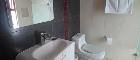Une salle de bain moderne avec une baignoire blanche, des toilettes et un porte-serviettes.
