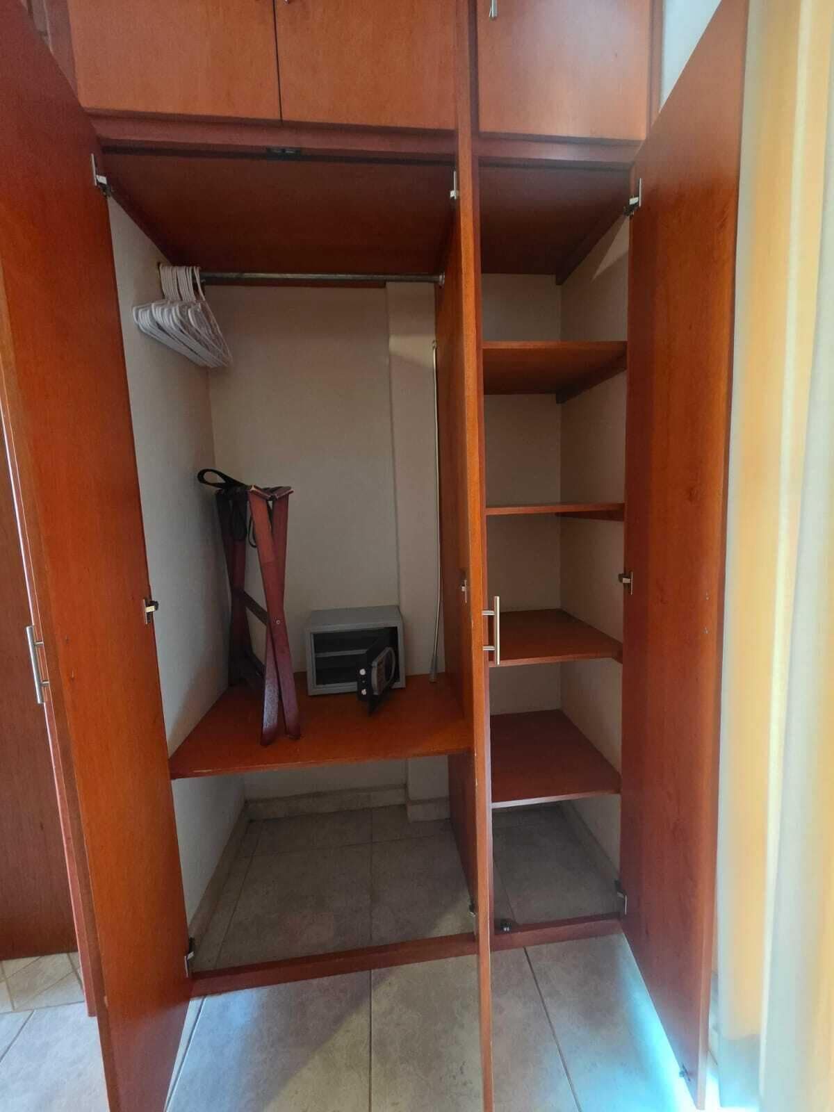 Een houten garderobe met meerdere planken en een kleine magnetron op het onderste plank.
