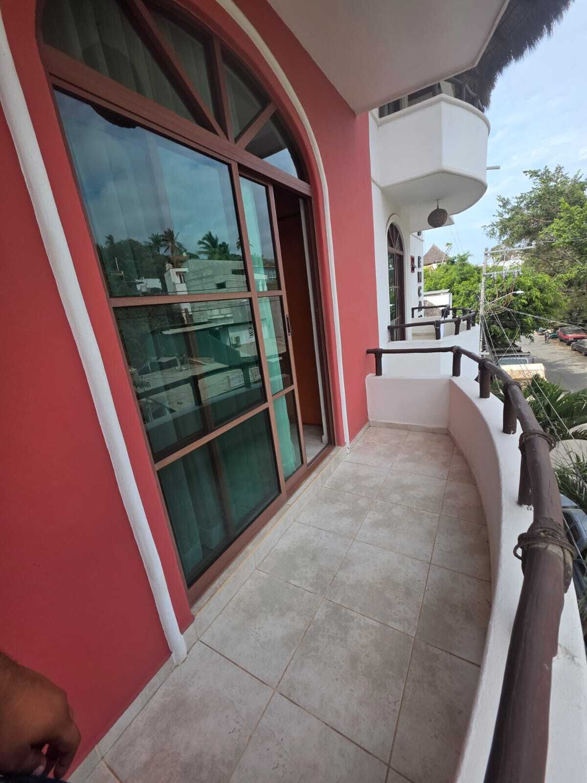A building with a large glass door, a balcony with a railing, and a tiled floor.