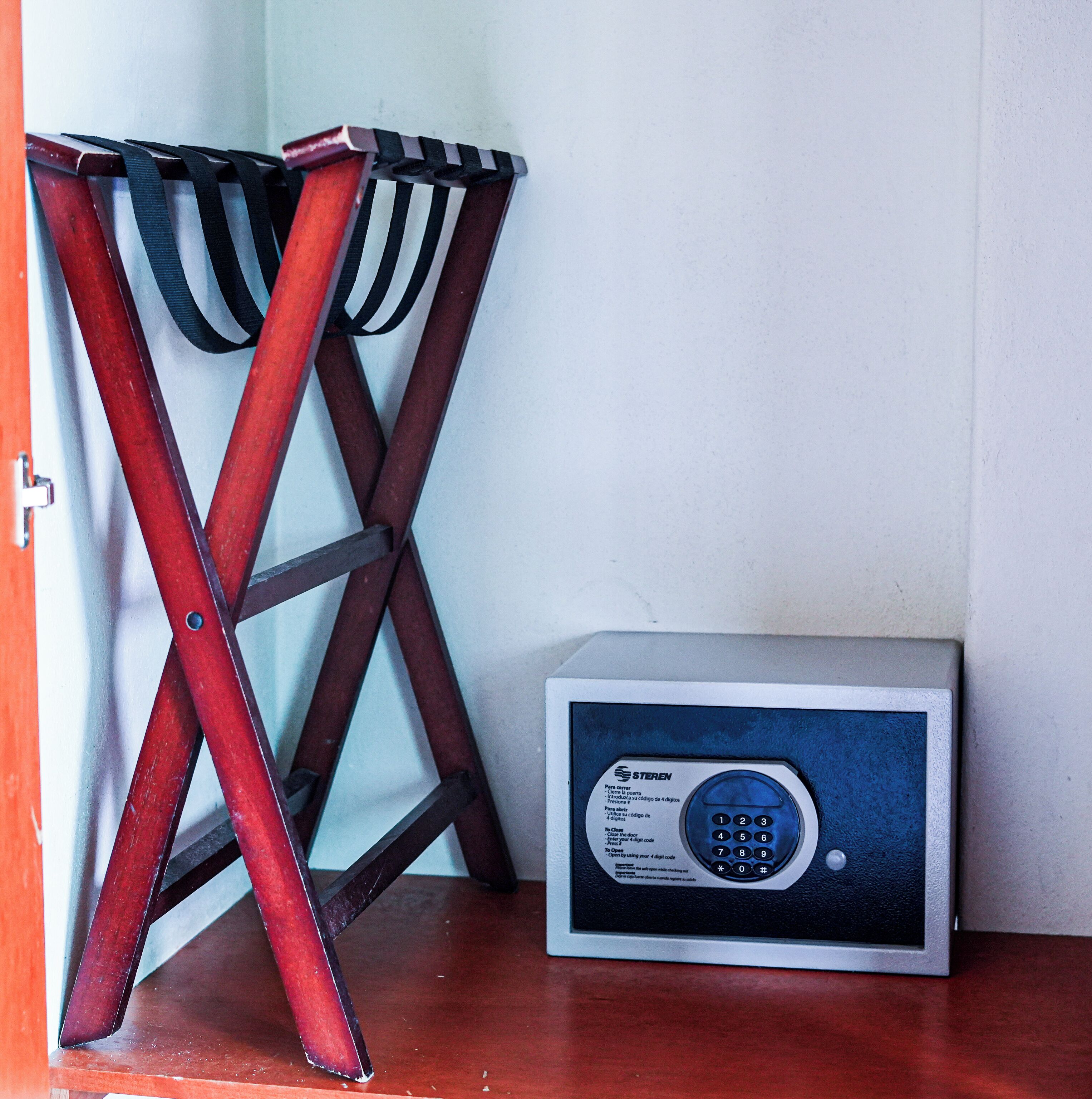 Una silla plegable de metal con asiento a rayas blancas y negras y un pequeño dispositivo electrónico con teclado e instrucciones en español.