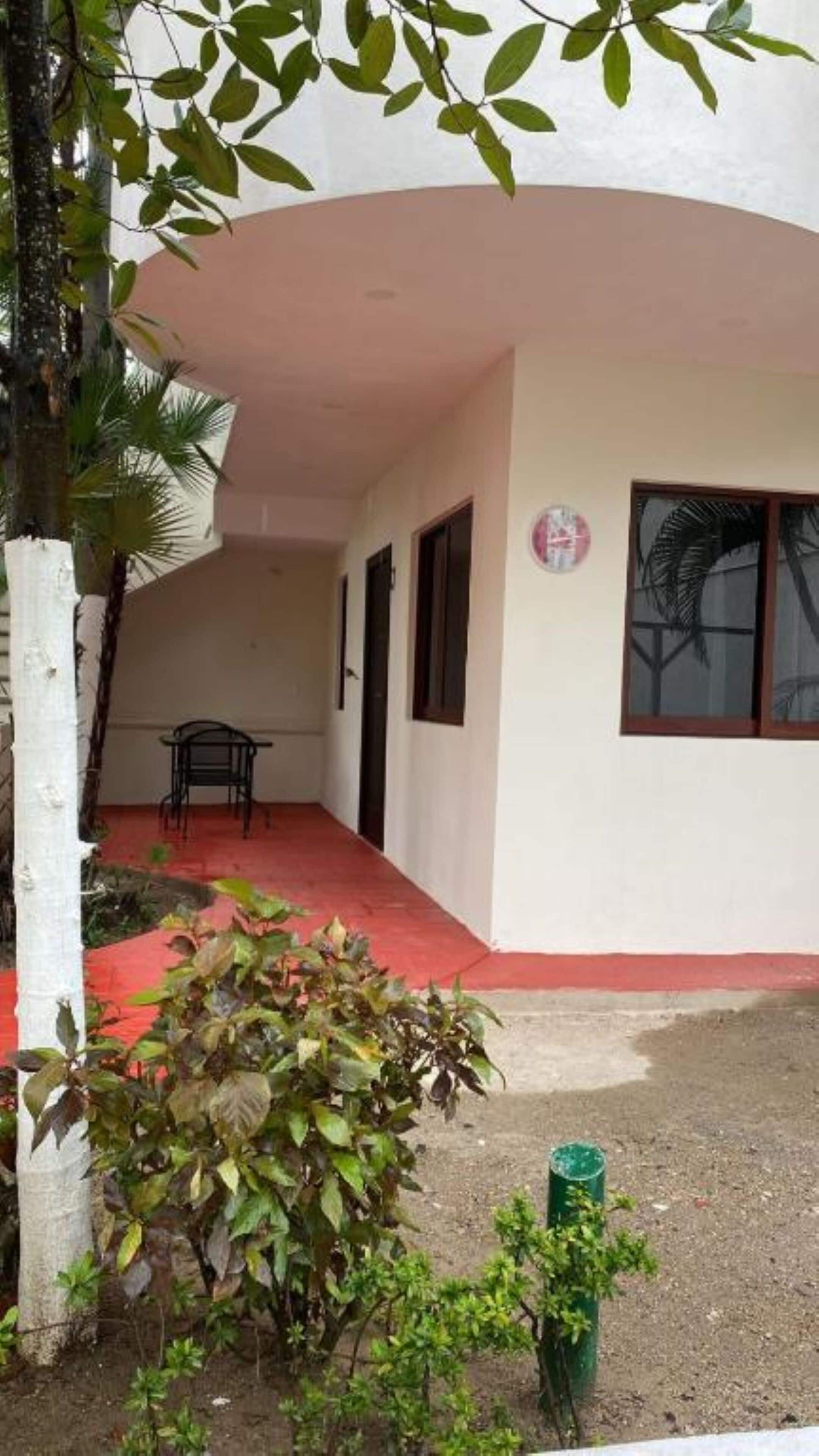 Un bâtiment doté d’un toit incurvé, d’un petit patio avec une table et des chaises, et d’un sol peint en rouge.