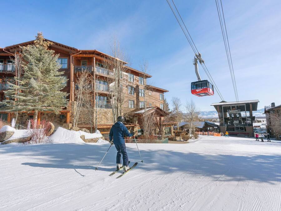 Een wintersportgebied met een skilift, houten gebouwen en een sneeuwbedekte grond.