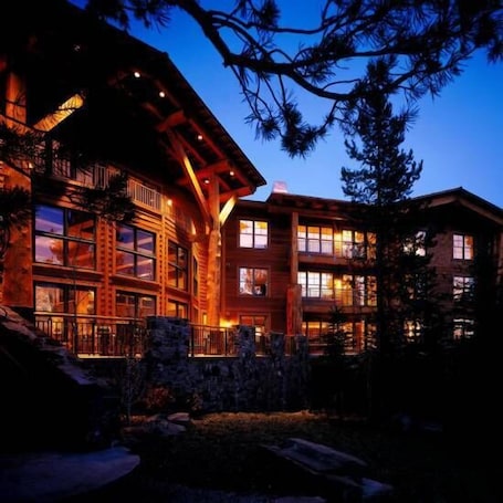 A multi-story lodge with a rustic exterior, large windows, and a stone foundation.
