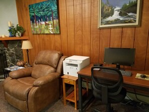 A home office with a brown leather chair, a desk with a computer, a printer, and a bookshelf.
