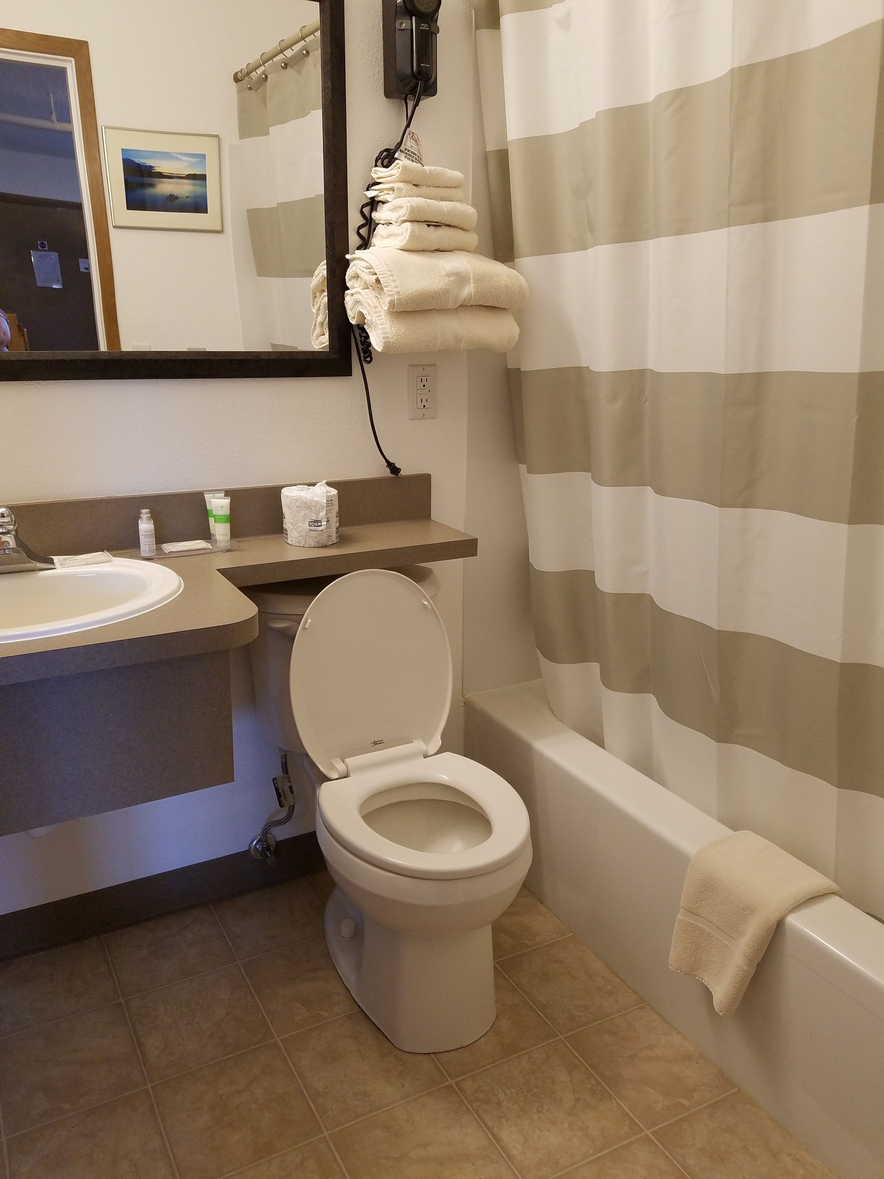 Une salle de bain équipée de toilettes, d’un lavabo et d’un porte-serviettes avec des serviettes pliées.