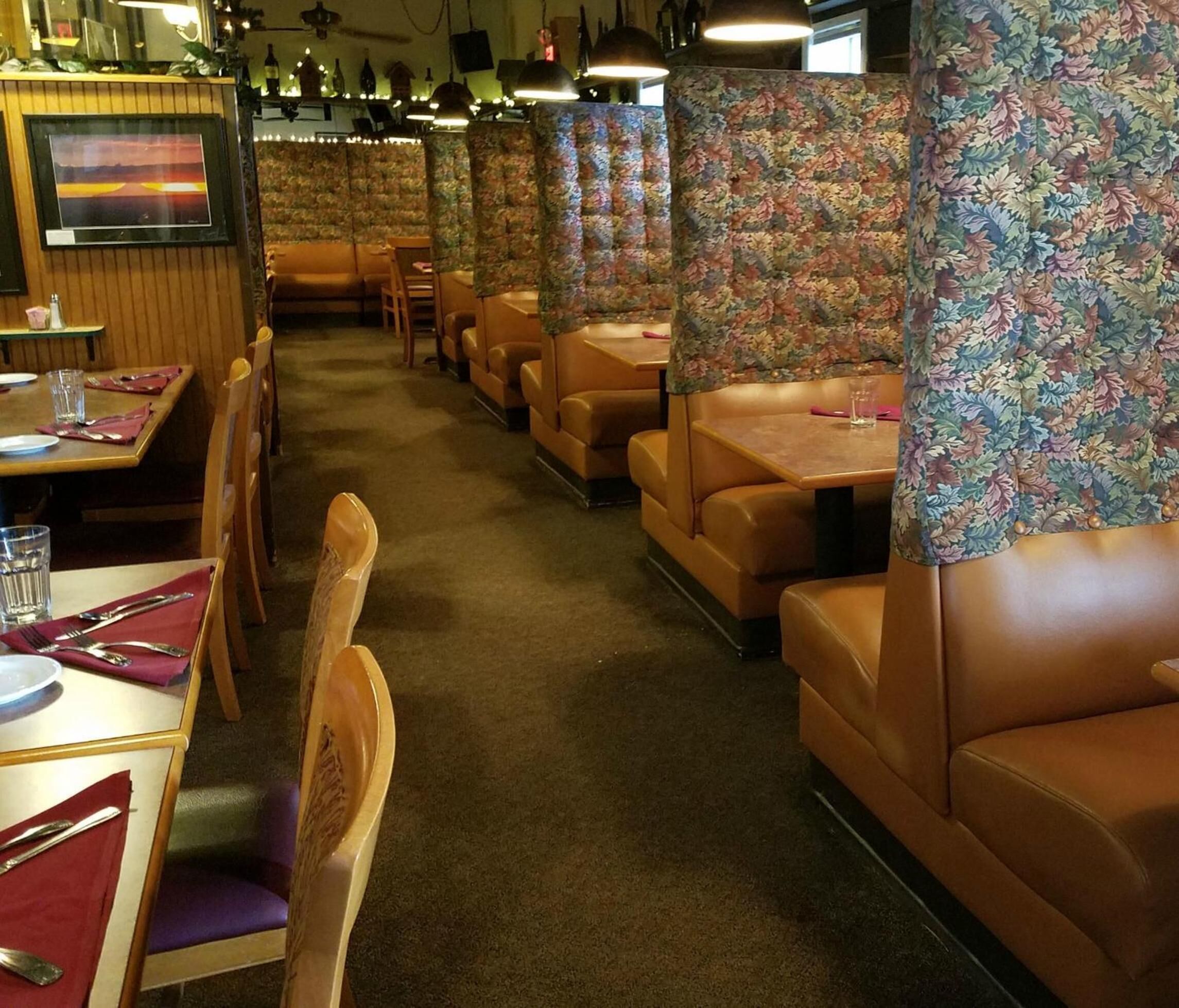 Un restaurant avec des banquettes et des tables, certaines séparées par des cloisons ornées de motifs floraux.