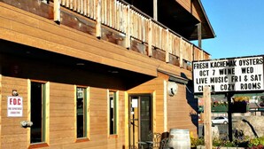 A wooden building with a sign advertising fresh oysters, wine, live music, and cozy rooms. - Soldotna Inn (Soldotna)