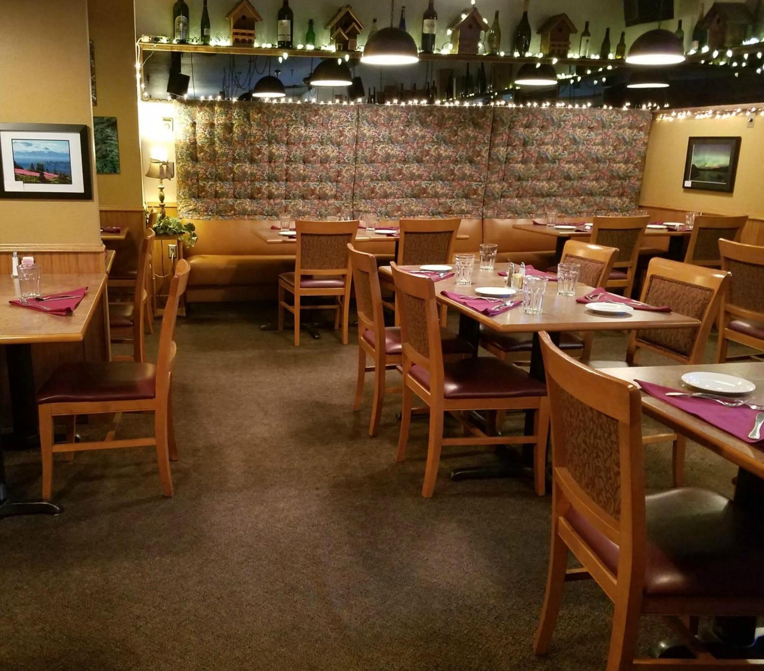 Un restaurante con mesas y sillas de madera, papel tapiz floral y luces colgantes en el techo.