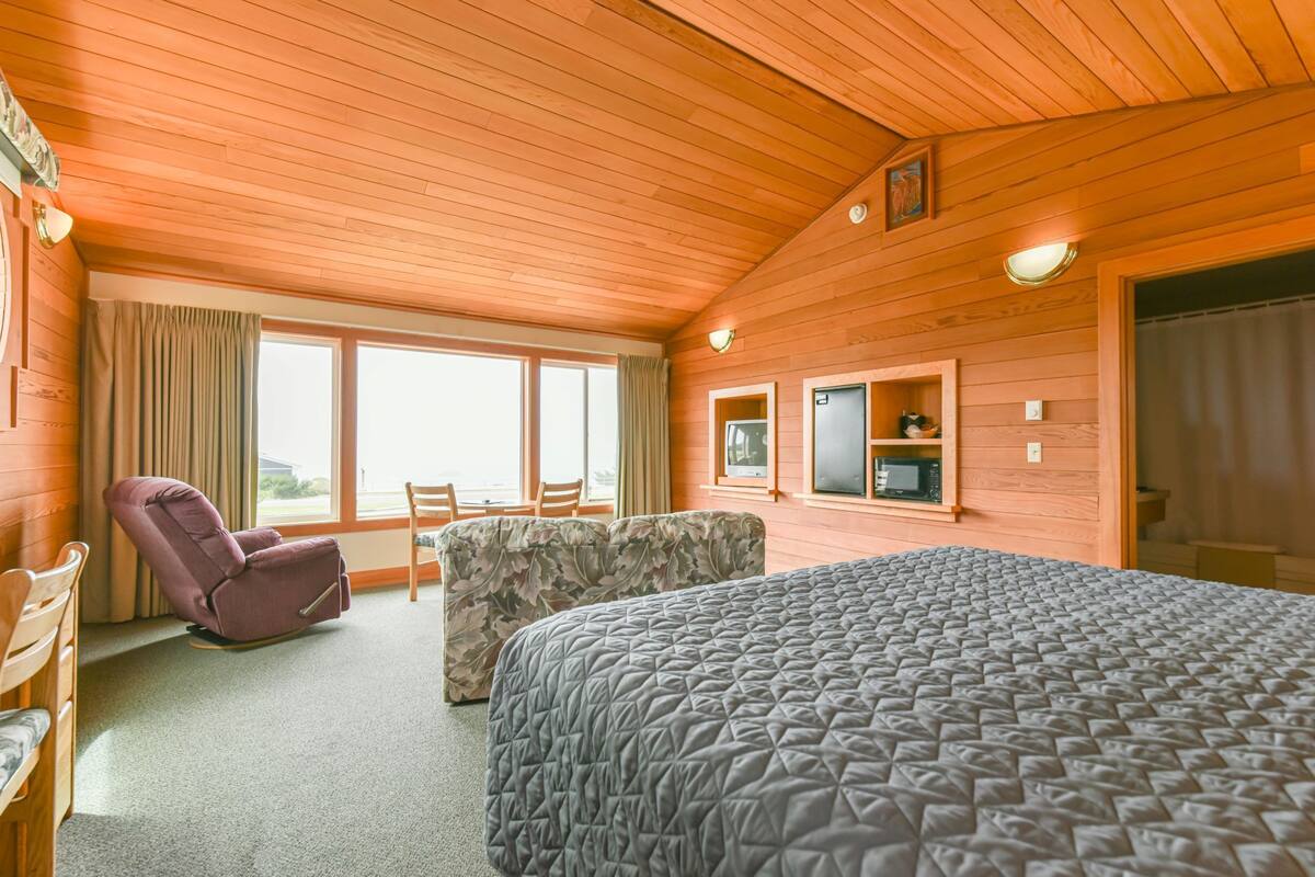 A room with a bed, a chair, a couch, and a television.