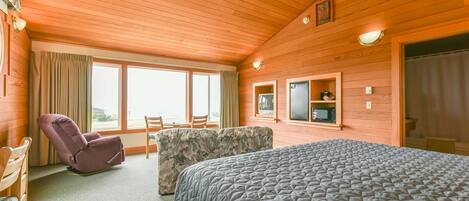 Una habitación con cama, sillón, sofá y televisor.