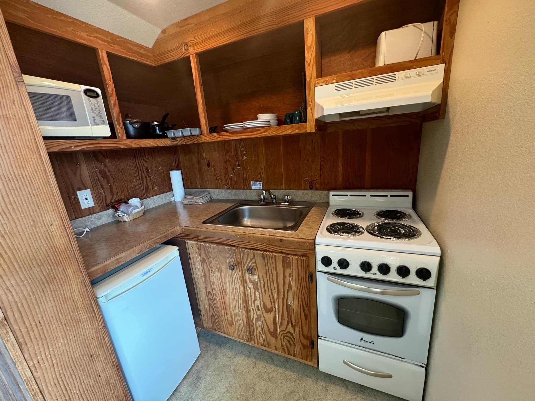 A compact kitchen with a built-in microwave, stove, and sink.