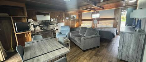 A cozy cabin interior with a dining table, sofa, and a bed.