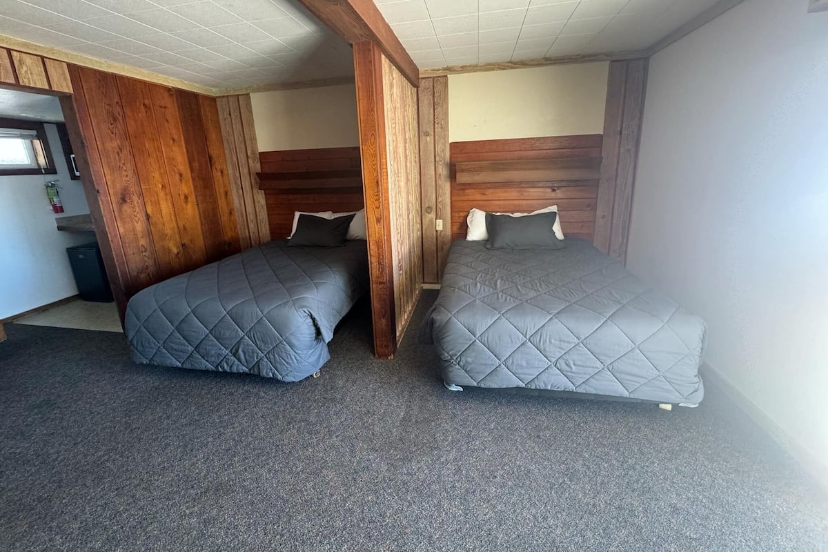 A room with two beds, wooden headboards, and a tiled ceiling.
