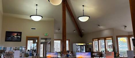 A spacious office with multiple desks, computers, and natural light from large windows.