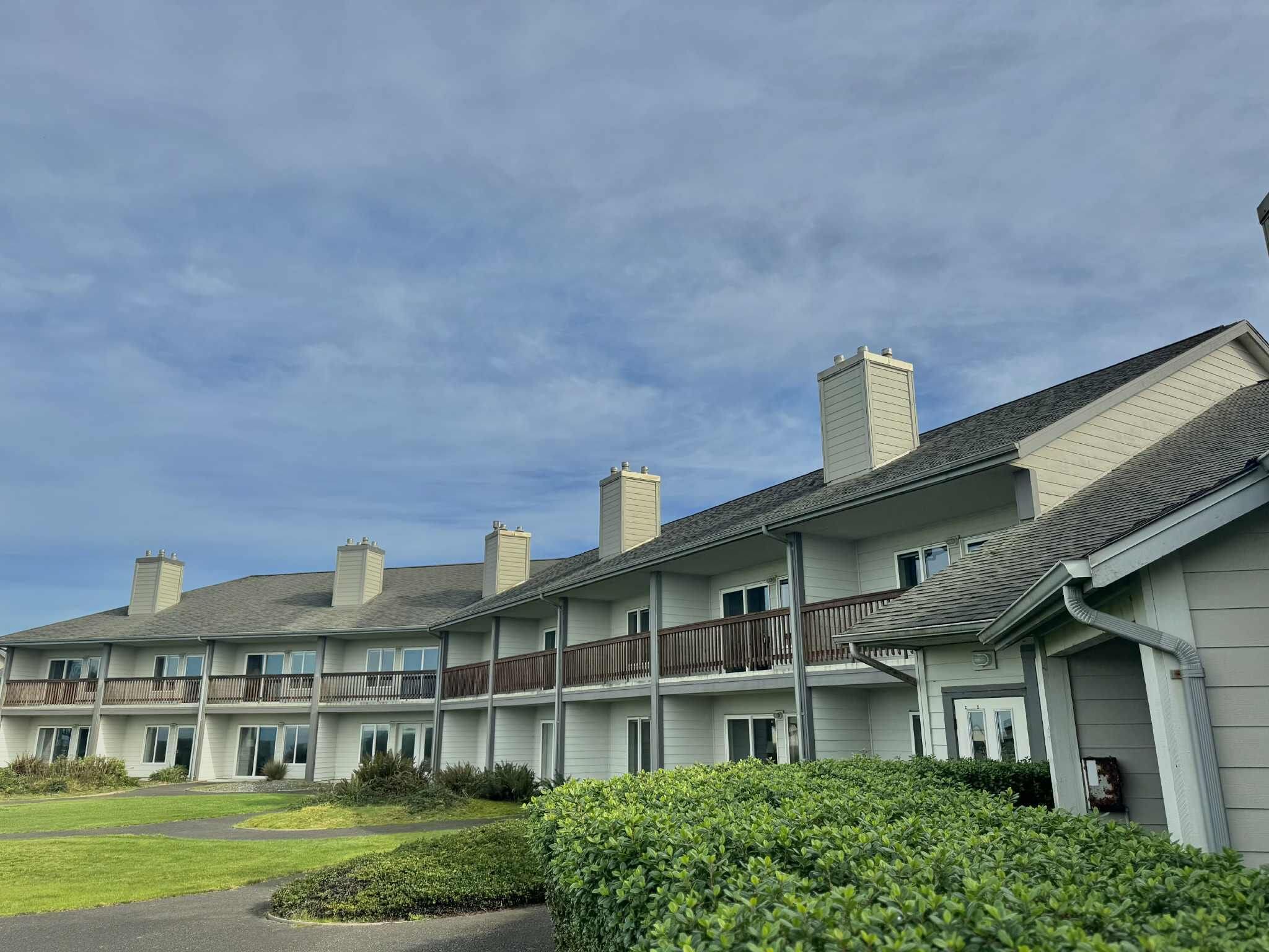 A multi-story residential building with a flat roof, multiple chimneys, and a balcony on the second floor.