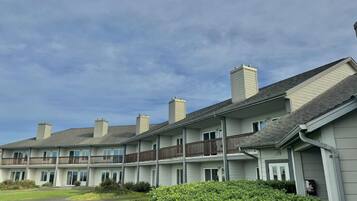 A multi-story residential building with a flat roof, multiple chimneys, and a balcony on the second floor.