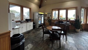 A kitchen with a refrigerator, microwave, and dining area with chairs and a table.