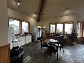 A kitchen with a refrigerator, microwave, and dining area with chairs and a table.