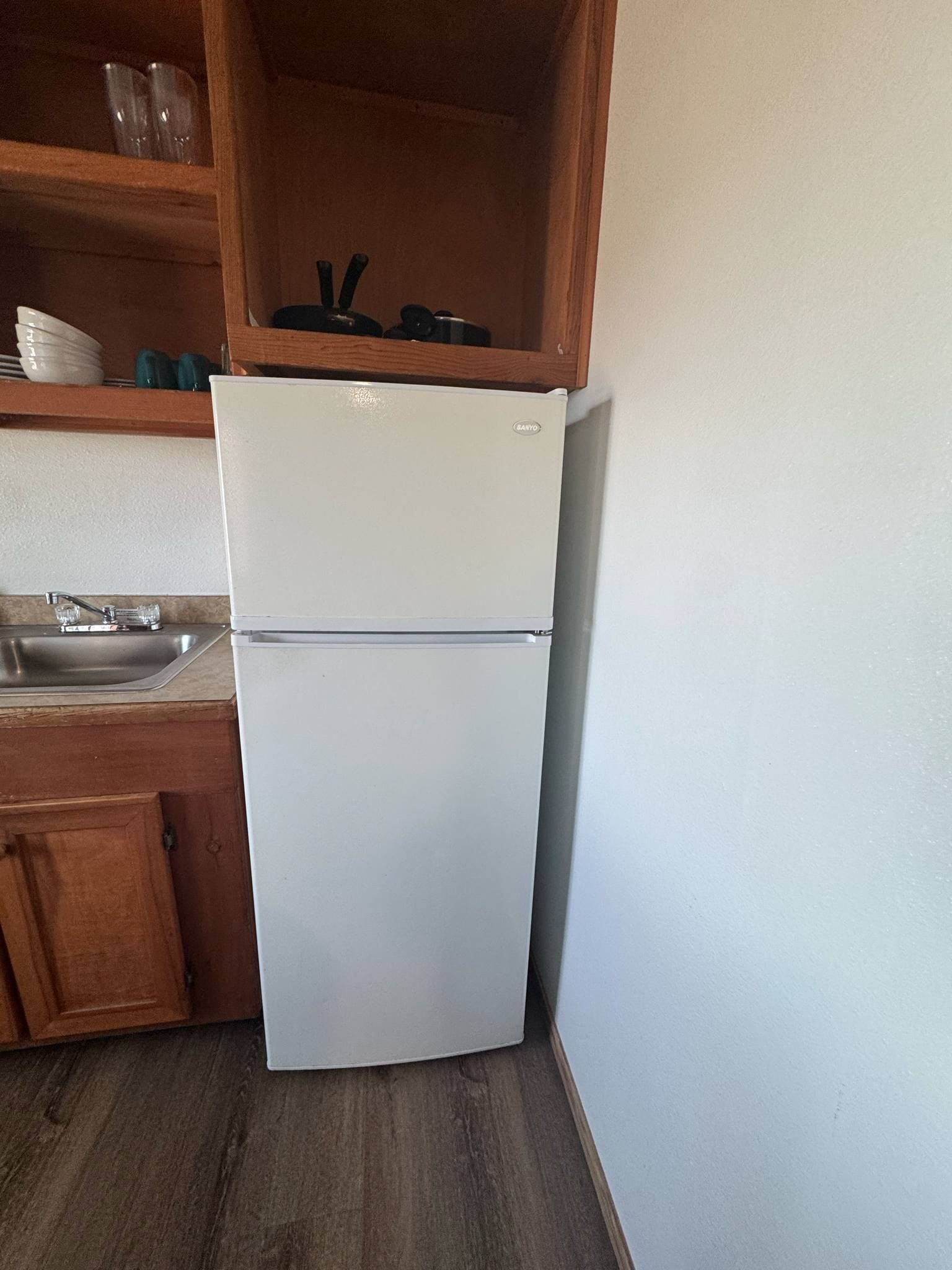 Una cucina compatta con frigorifero bianco, mobili in legno e lavello in acciaio inossidabile.