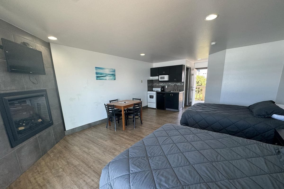 A compact room with two beds, a dining table, and a kitchenette.