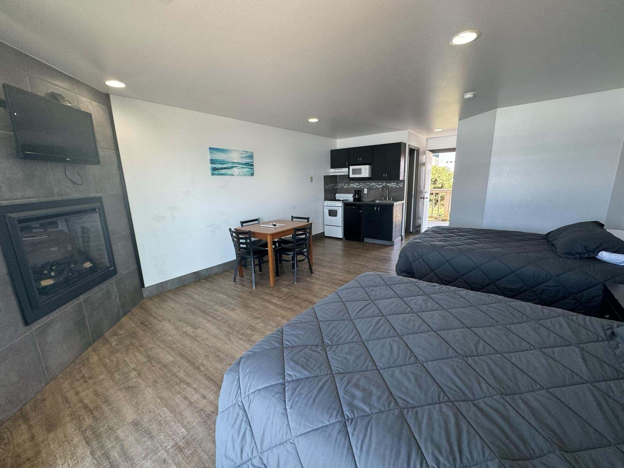 A compact room with a kitchenette, a dining area, and two beds.