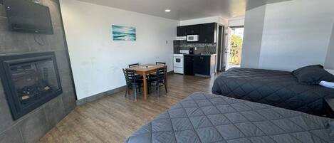A compact room with a kitchenette, a dining area, and two beds.