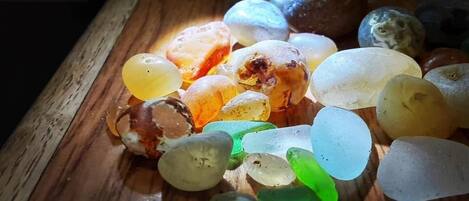 A collection of translucent, multicolored glass pebbles on a wooden surface.