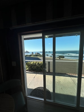 A room with a large sliding glass door leading to a beach view. - Sunset Oceanfront Lodging (Bandon)
