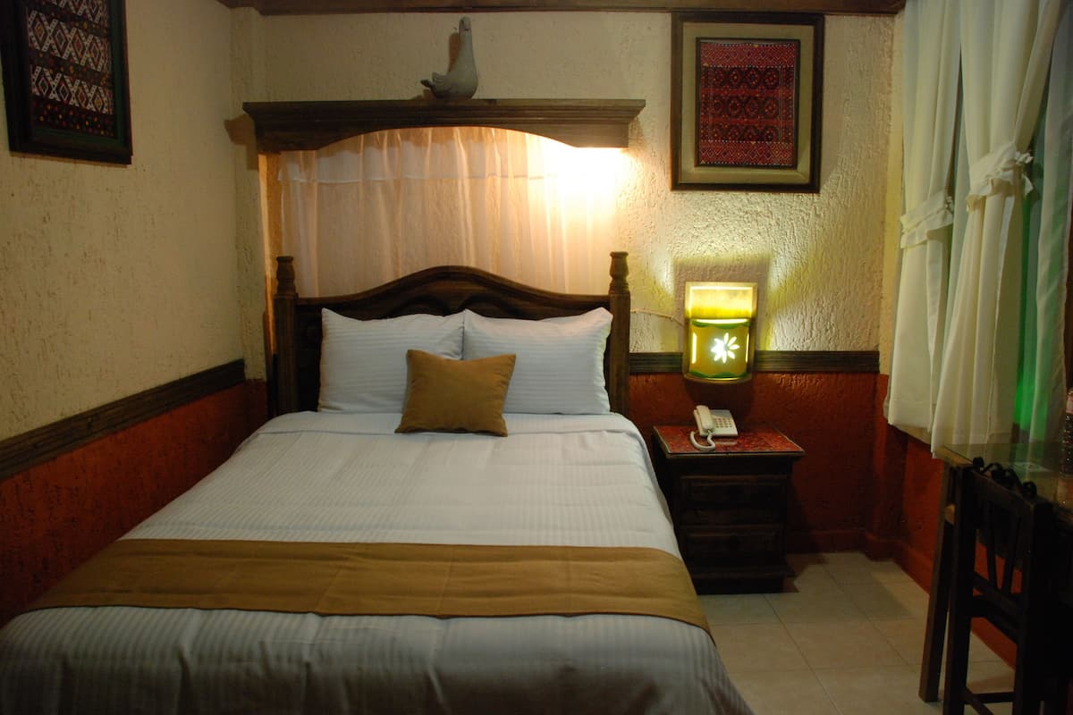 A neatly made bed with a wooden headboard, a bedside lamp, and a telephone on a nightstand.