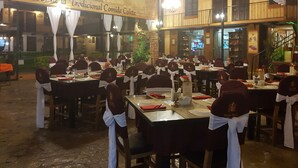 A restaurant with multiple tables set for dining, featuring white tablecloths and red napkins. - Hotel Mision Colonial San Cristobal (San Cristóbal de las Casas)