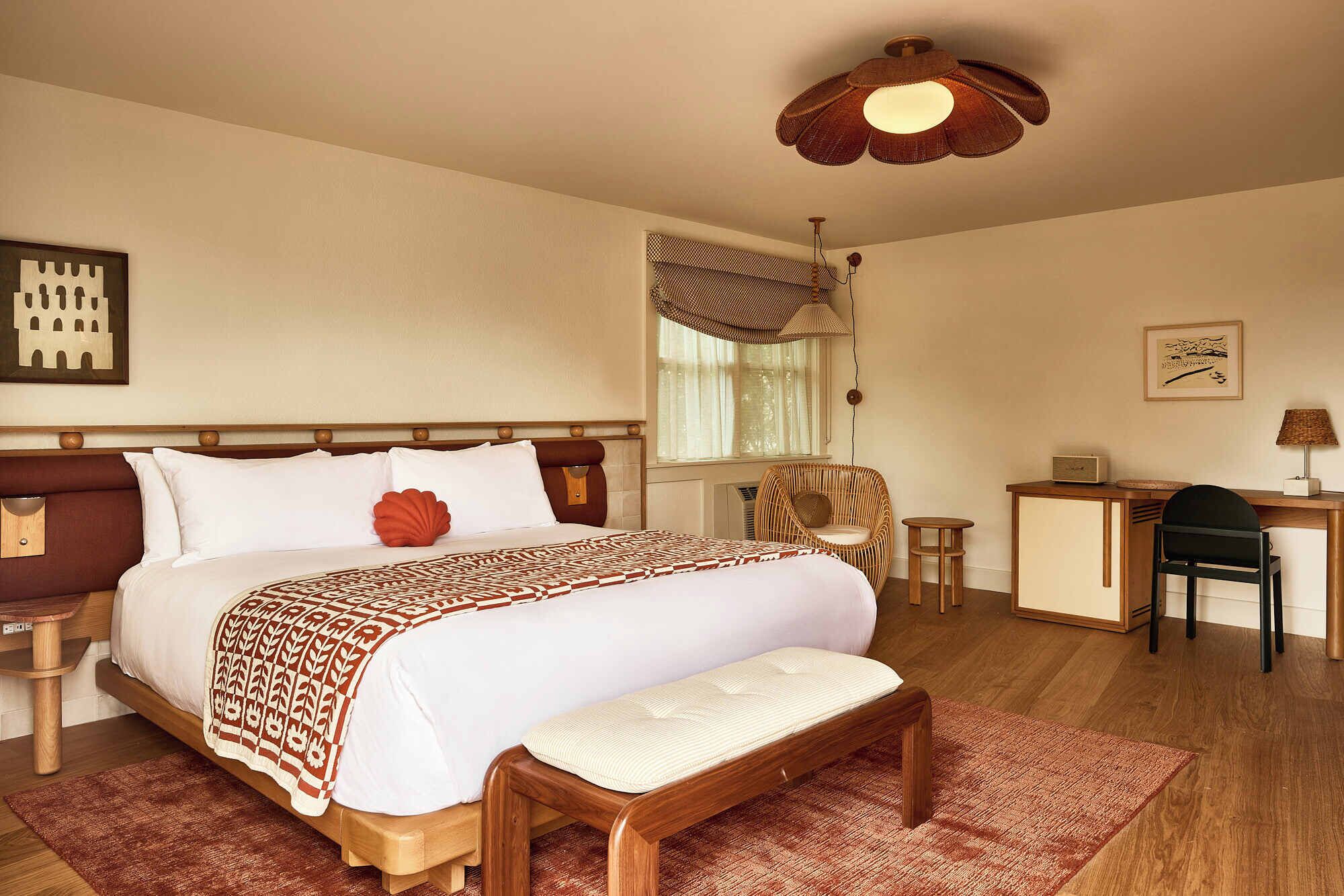 Ein Hotelzimmer mit einem großen Bett, einem Schreibtisch, einem Sessel und einem kleinen Tisch.