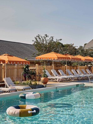 A swimming pool with lounge chairs and orange umbrellas. - The Beachside (Nantucket)