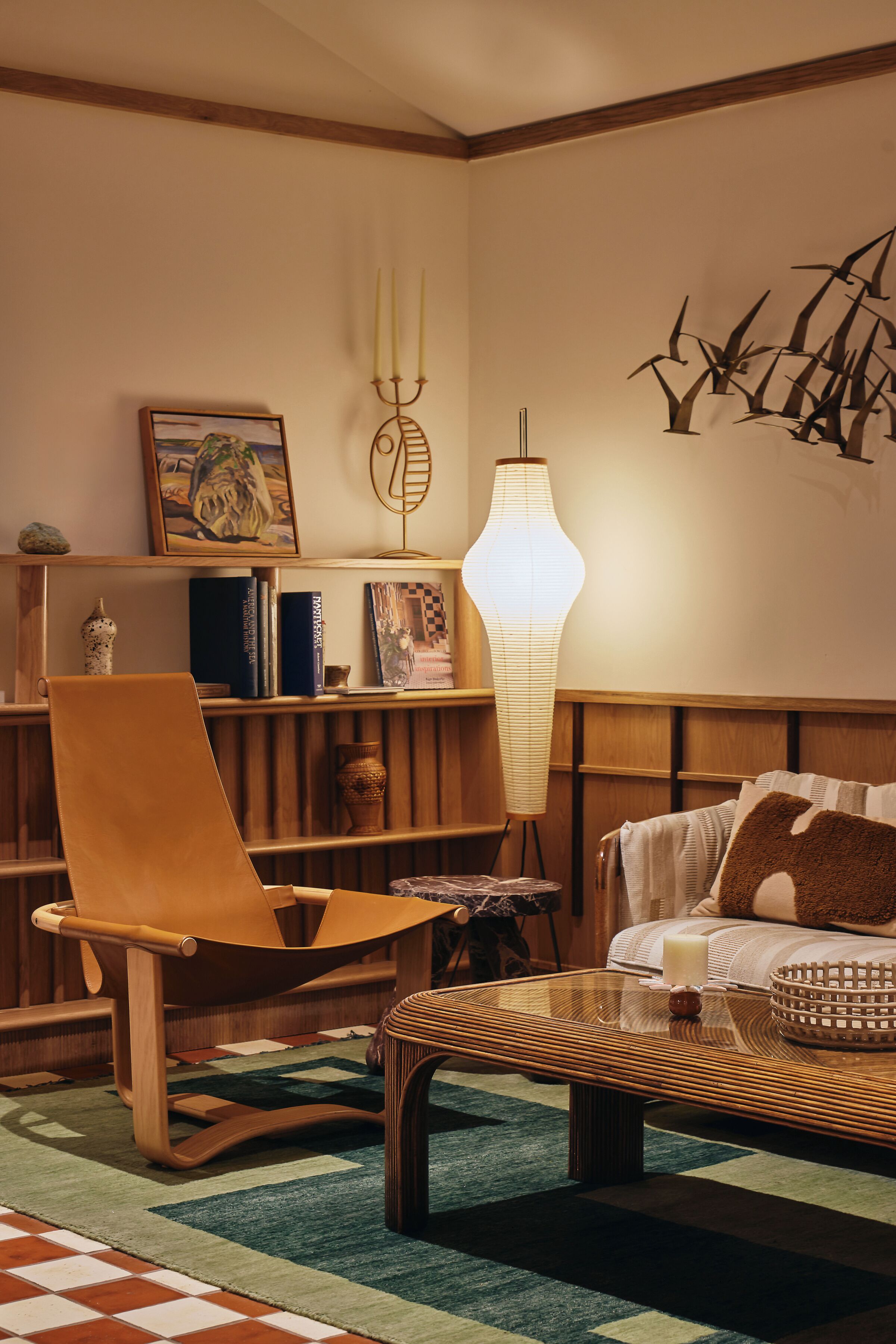 Una sala de estar acogedora con una silla de madera, un sofá, una mesa de centro y una estantería.
