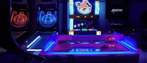 A row of arcade machines with neon lights, including Angry Birds and other games.