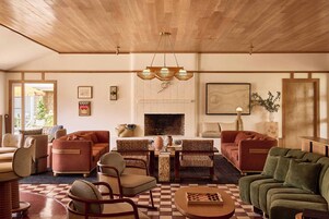 Un salón amplio con chimenea, techo de madera y suelo a cuadros.