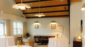 A cozy room with a wooden ceiling, a sofa, and two round tables with candles. - The Beachside (Nantucket)