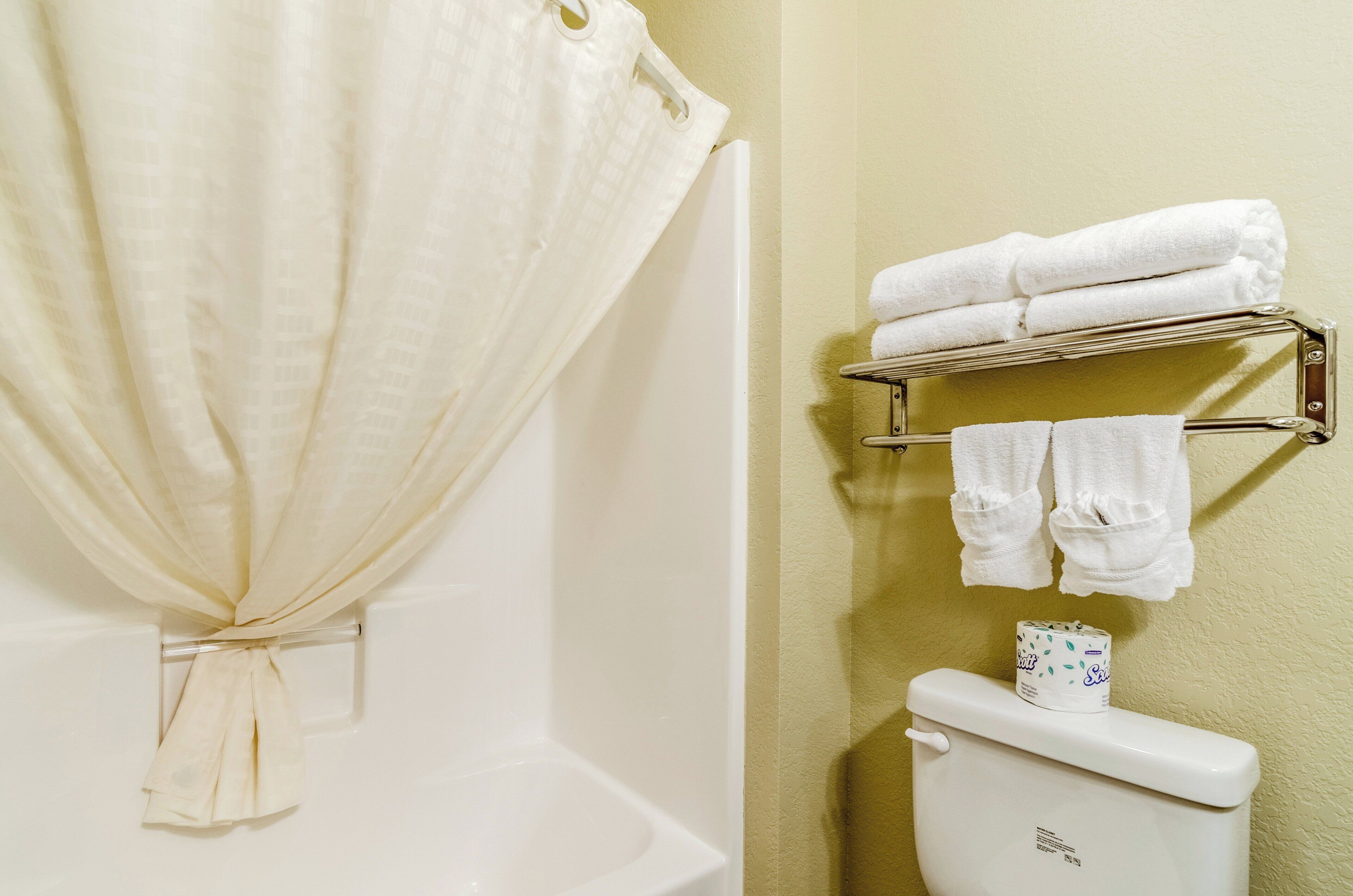 A bathroom with a shower curtain, a toilet, and a towel rack with towels.