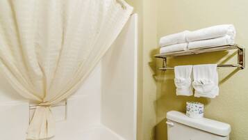 A bathroom with a shower curtain, a toilet, and a towel rack with towels.